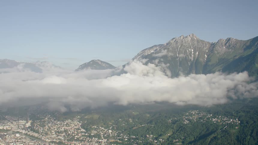Clouds pass between tall stone mountains above a village