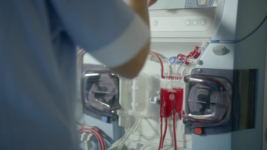 A nurse is punching buttons on a transfusion machine