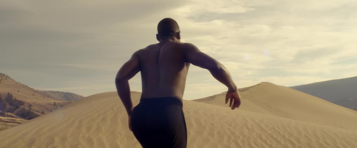 Shirtless man stumbles in desert