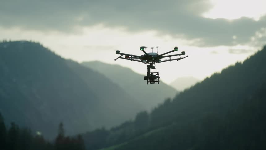 A drone is spinning over the mountains before flying forward