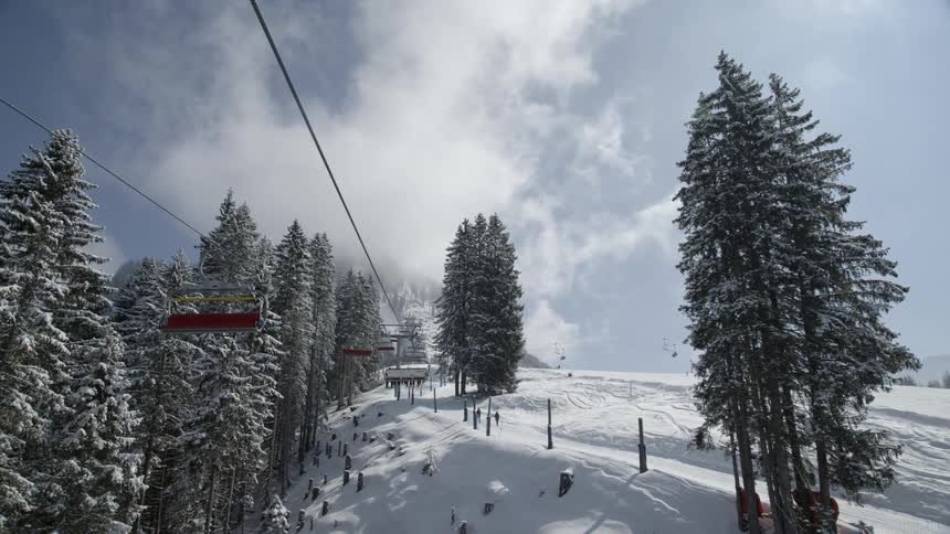 A ski lift hangs idle above a slope on a sunny day