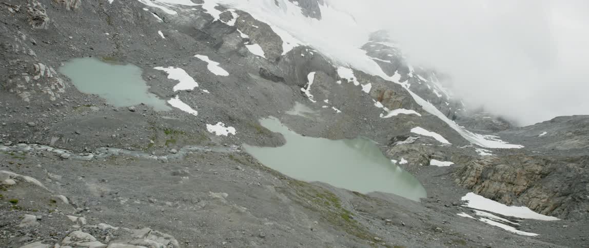 Water pools in crevices of a mountain covered with patches of snow