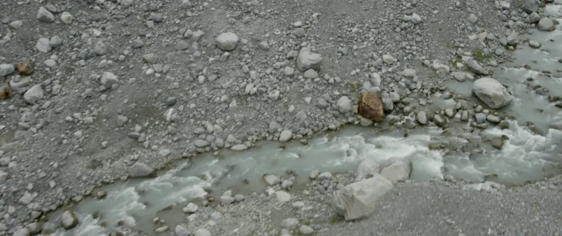 A stream rushes over rocks in a glacier landscape during the day
