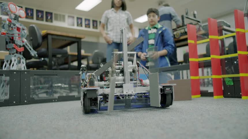 A team of people are controlling a small robot on wheels