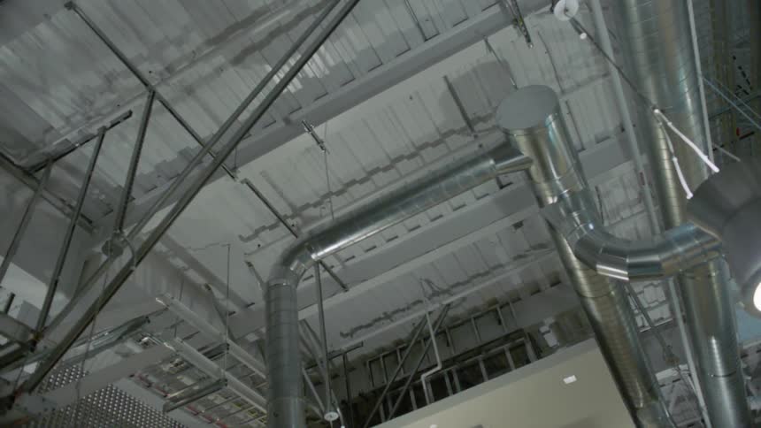 The warehouse has many vents and pipes along the ceiling