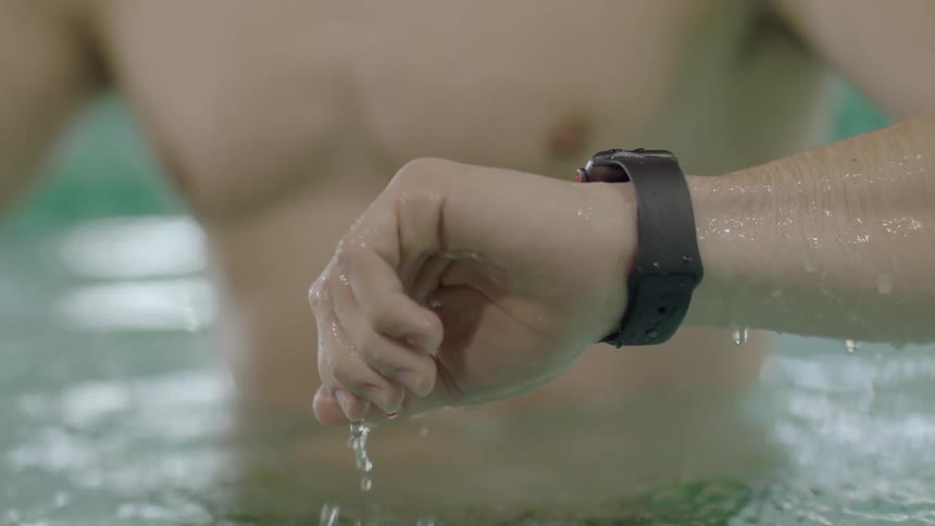 A man looks at his watch in a pool
