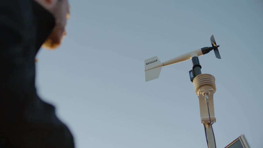 A man looks up at a wind vane