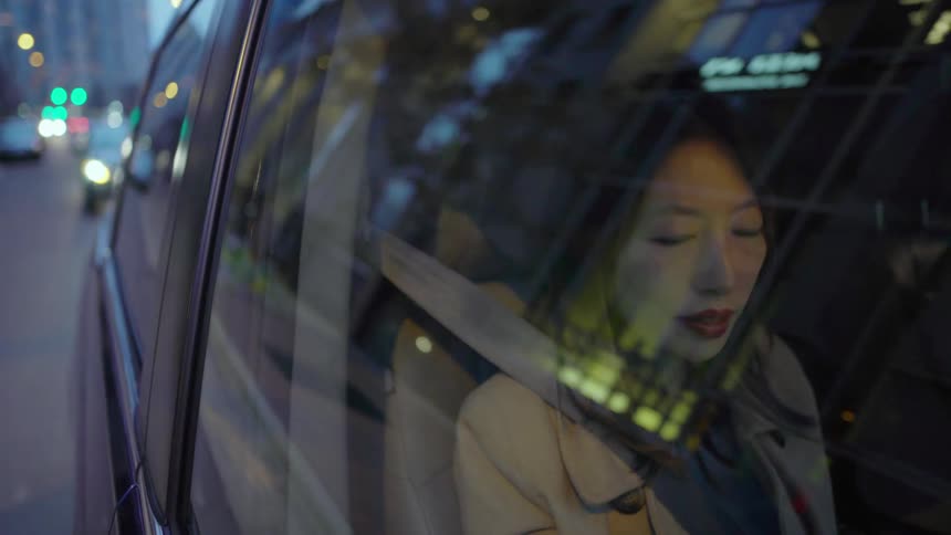 A woman is riding inside a cab and looking out the window