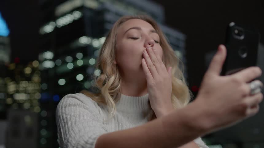 A woman looks at her phone and takes a selfie