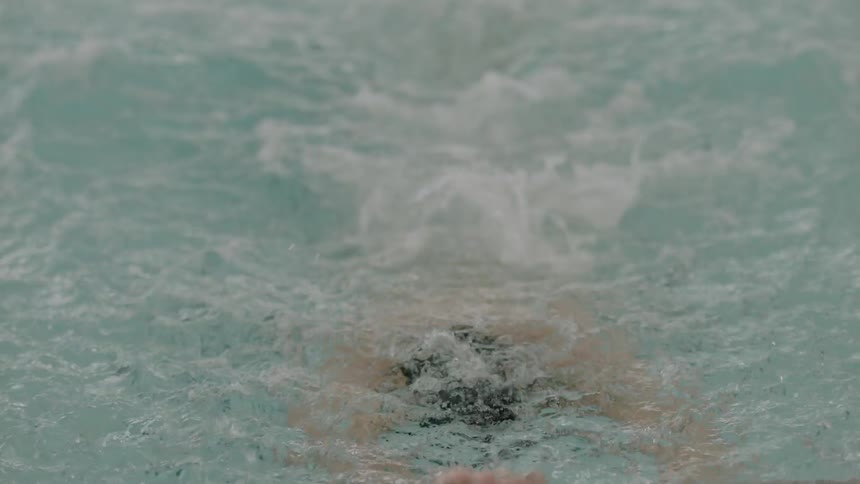 Man splashes and swims in a pool