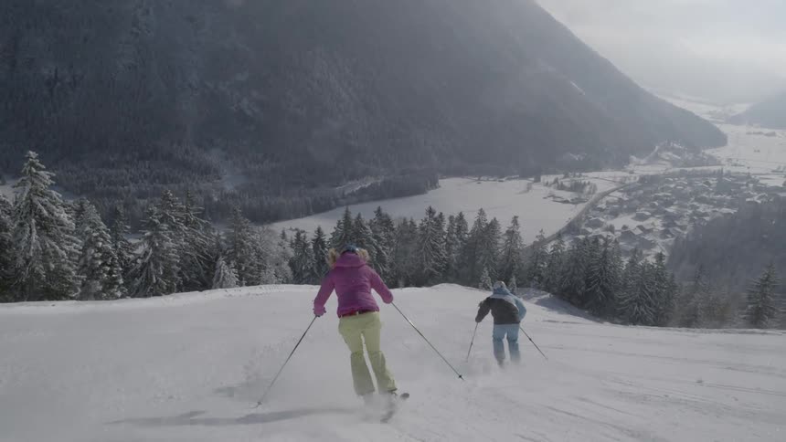 Skiers travel down the slope
