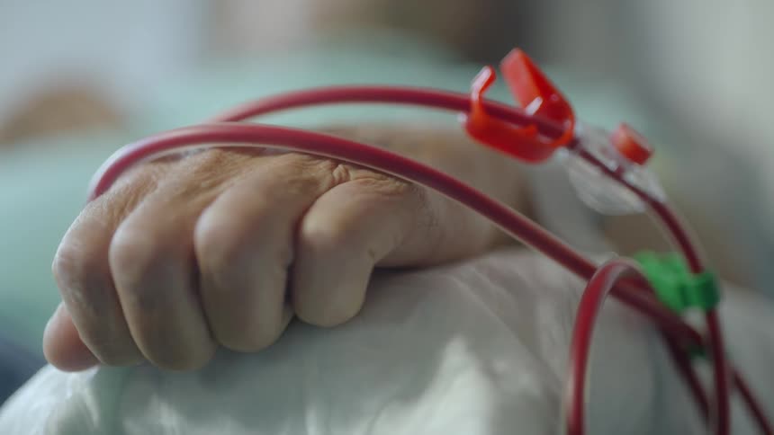 A patient receiving a transfusion is clenching their hand