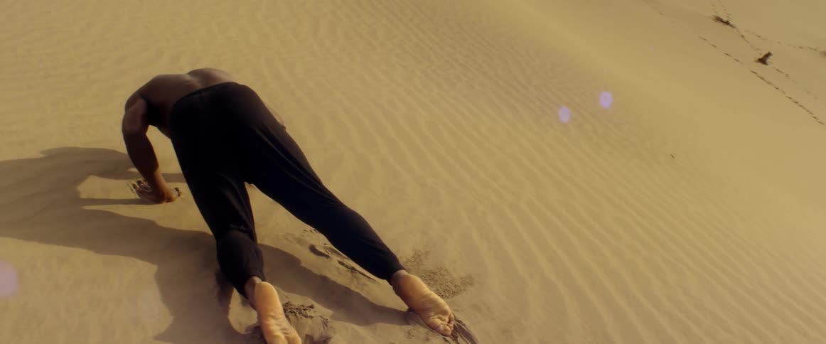 A man falls as he is walking on a sand dune on a cloudy day