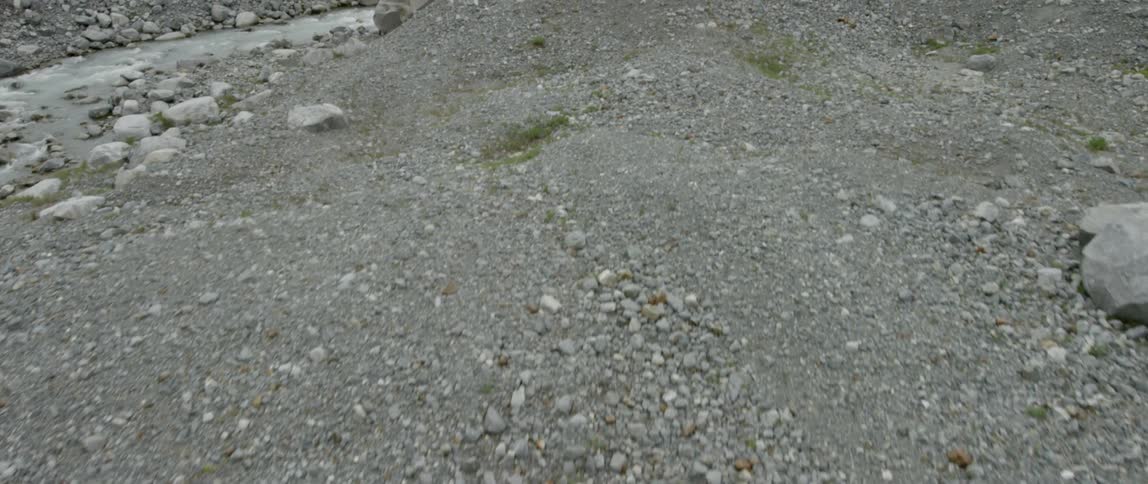 Gravel and rocks cover the ground next to a stream