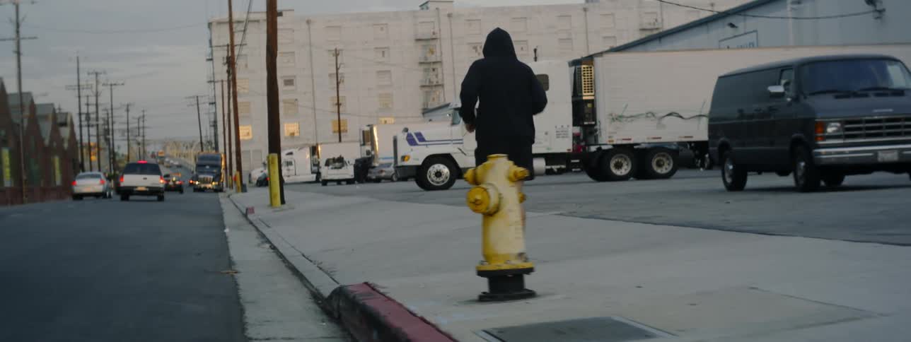 Man jogs down the sidewalk past some tractor trailers