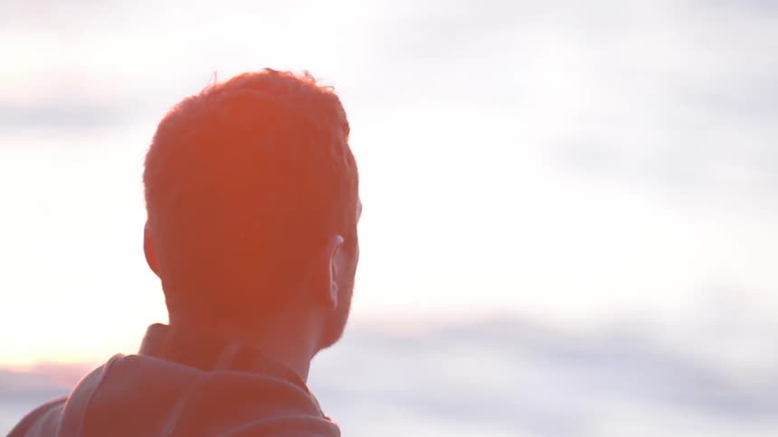 Man at the ocean looking out at sunset