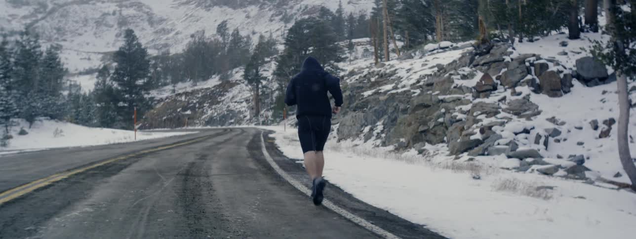 Man jogs on snowy mountain road