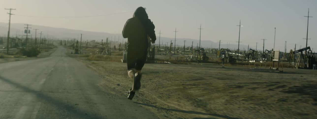 A man is jogging on the side of the small road