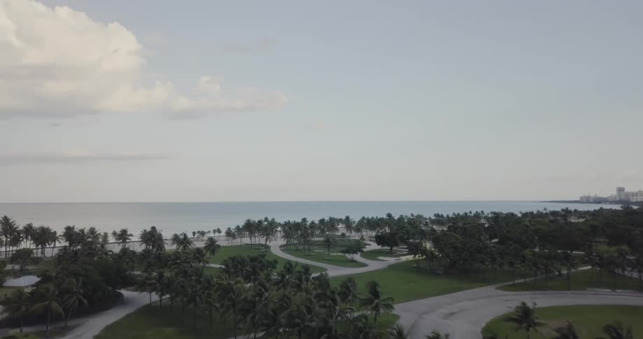 Park like area next to the sea with some clouds in the sky