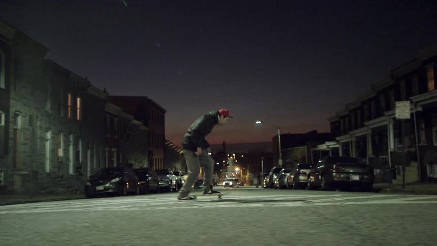 A man skateboards in the street at night over the crosswalk