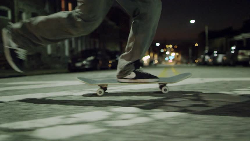 Skateboarder rides on a city street at night