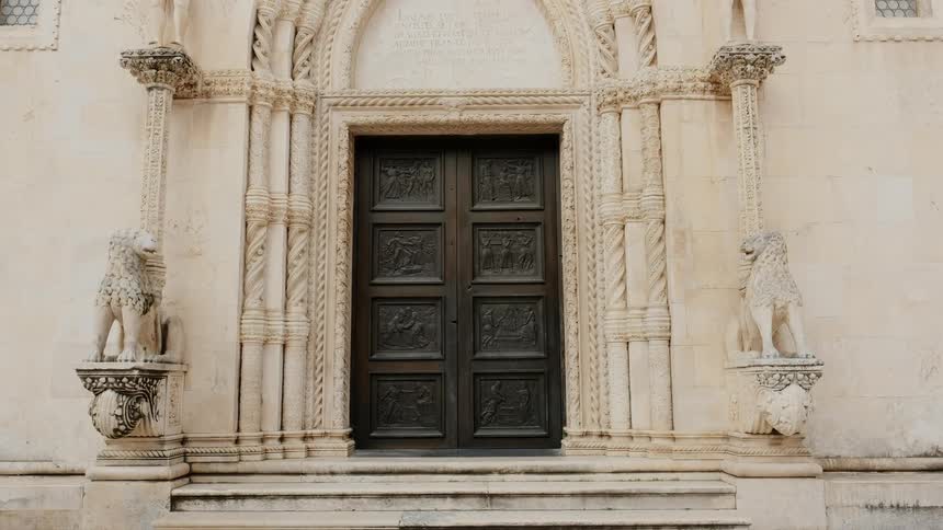 Two stone lions are standing guard before the wooden doors of an old building
