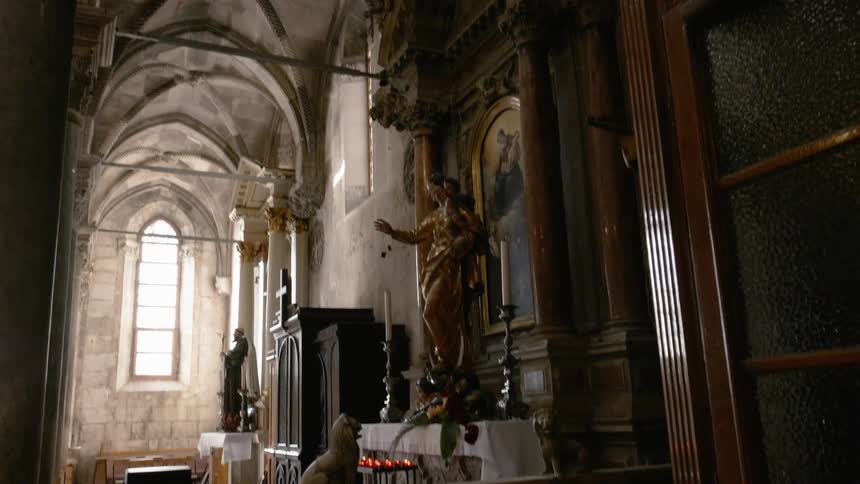 Candles are lit by a statue in an old church