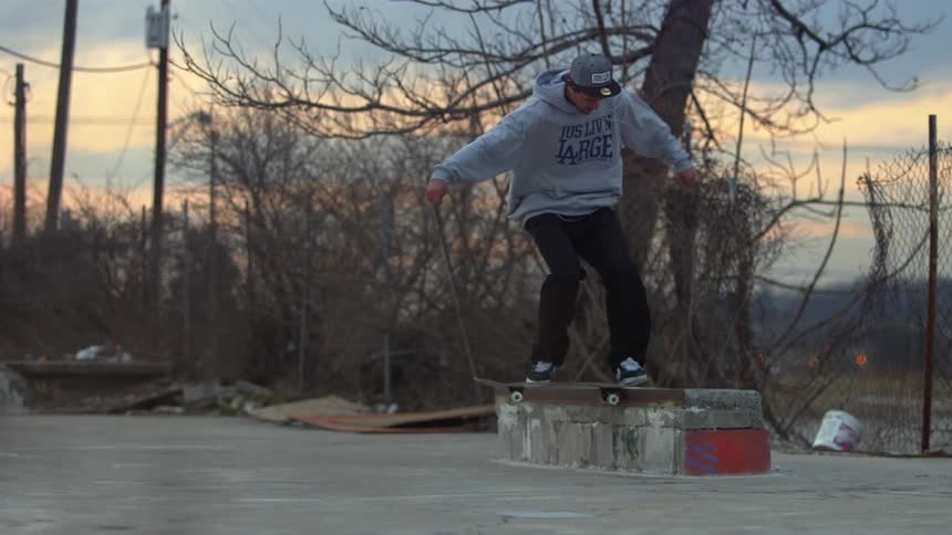 A skateboarder jumps and grinds on a concrete bench