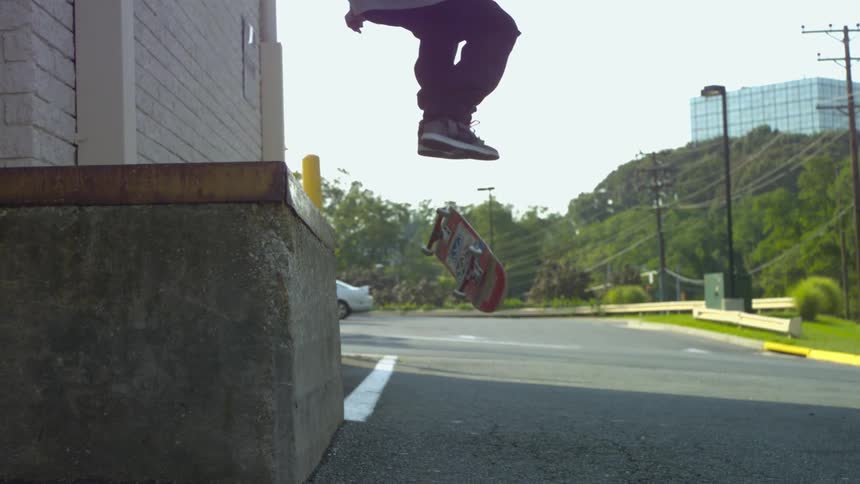 A skateboarder grinds his board off a ledge and lands on the board on the ground