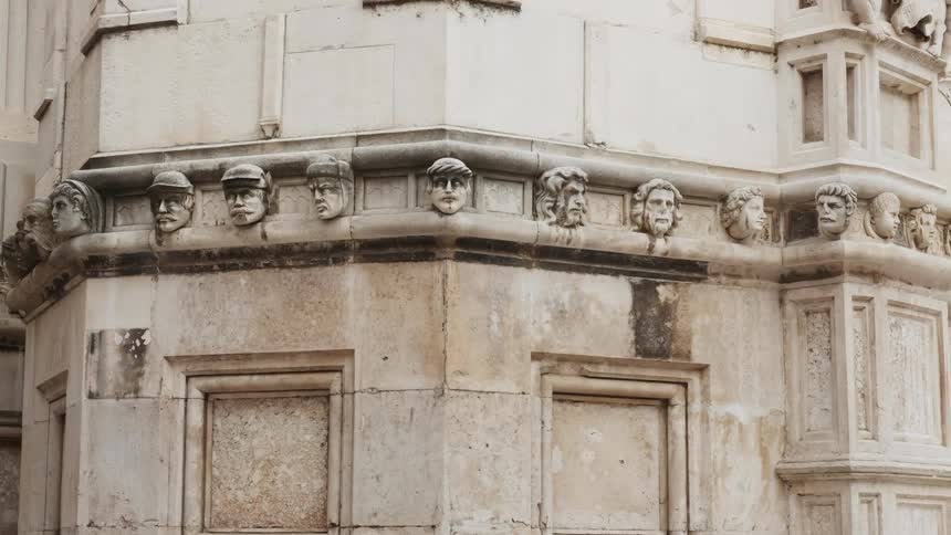Statues of heads cover a stone building