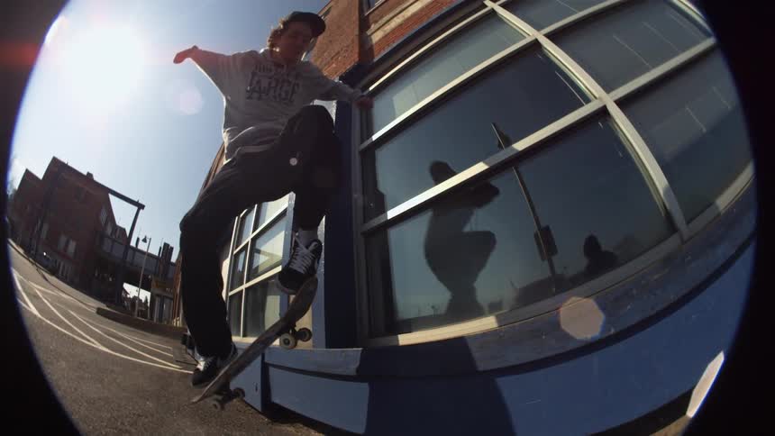Someone is riding a skateboard and jumps onto a ledge with it