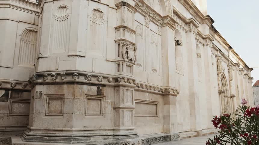 Flowers are planted near the large stone building