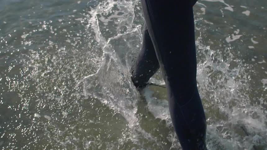 A person wearing a wet suit is walking through the water