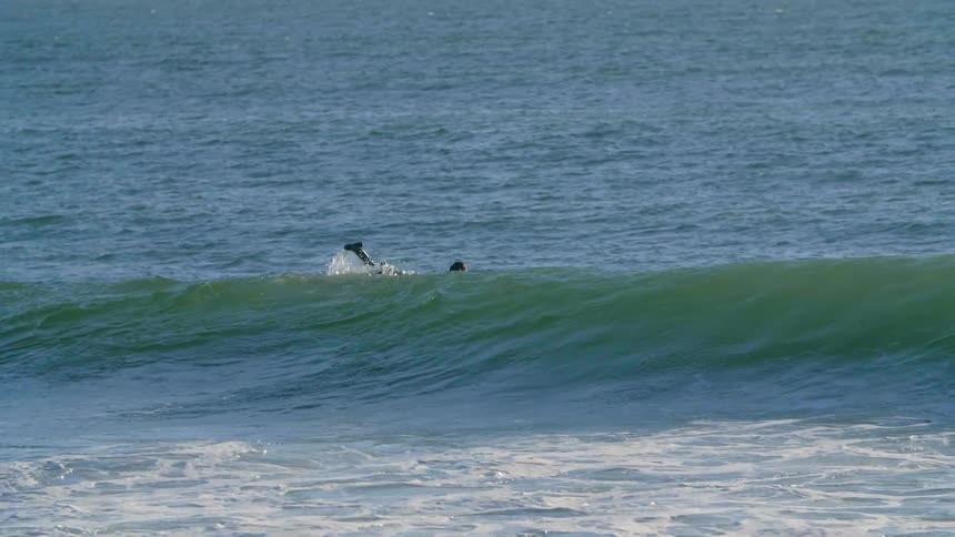A man is paddling out to catch some waves on his surfboard