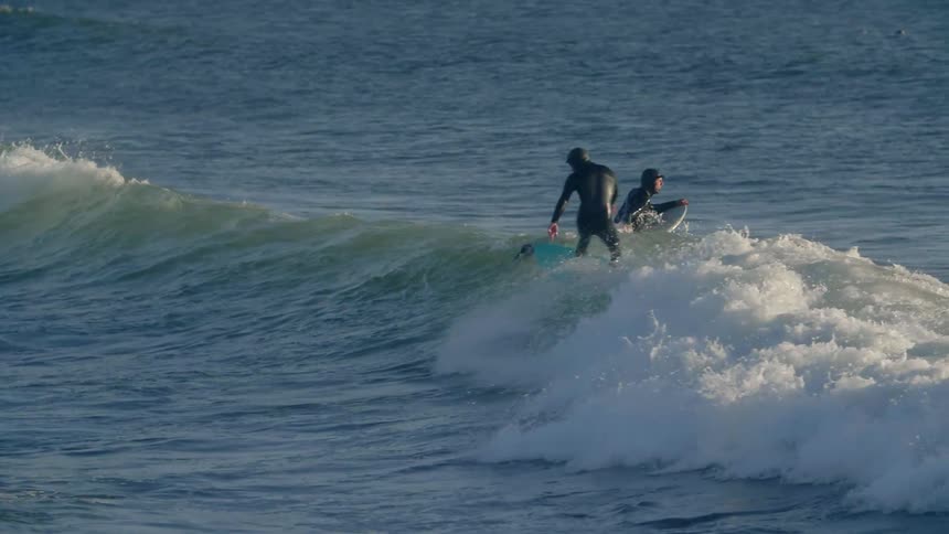 A surfer rides a wave towards the shore