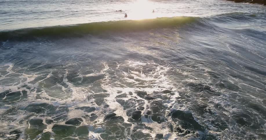 Surfers float in the water near the shore