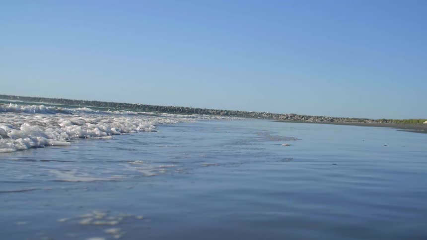 Waves roll onto the shore of a beach on a sunny day