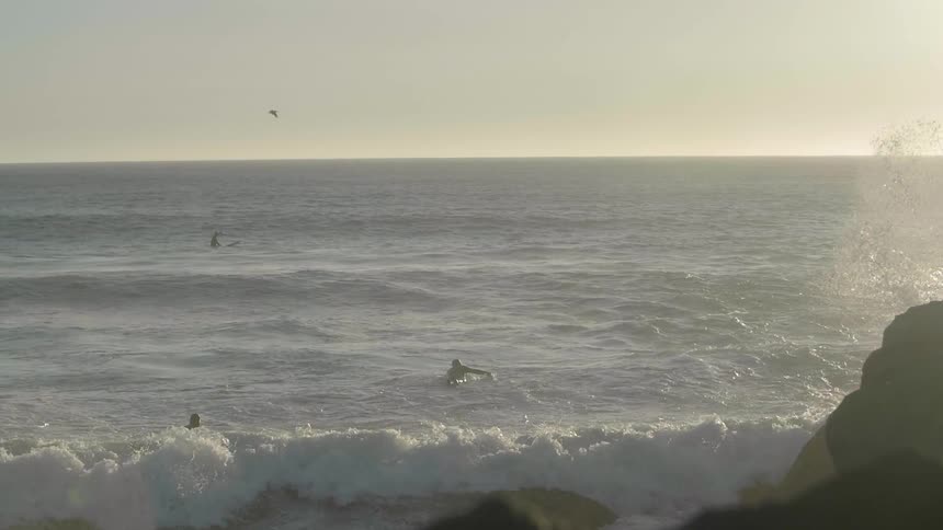 The surfers are trying to ride in the rough waters