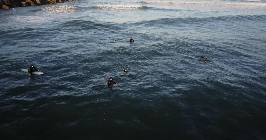 Surfers paddle on boards in the water