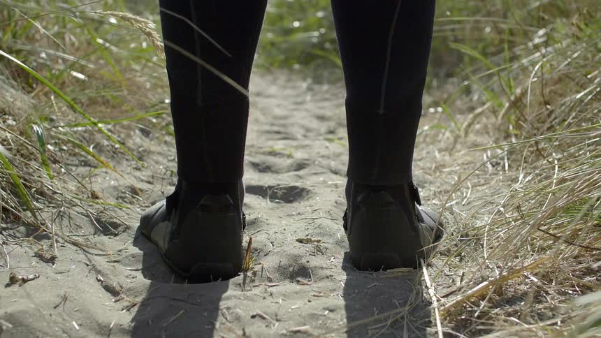 A person wearing a wetsuit is standing on beach sand