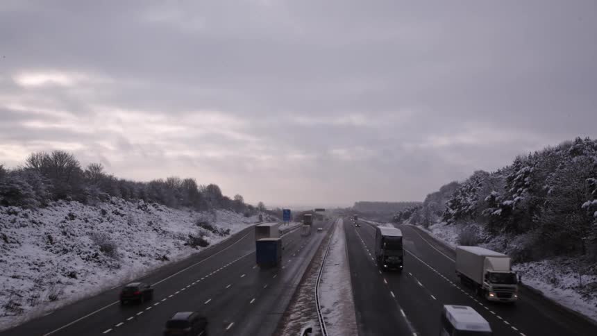 Traffic on a busy divided highway beside snowy hills