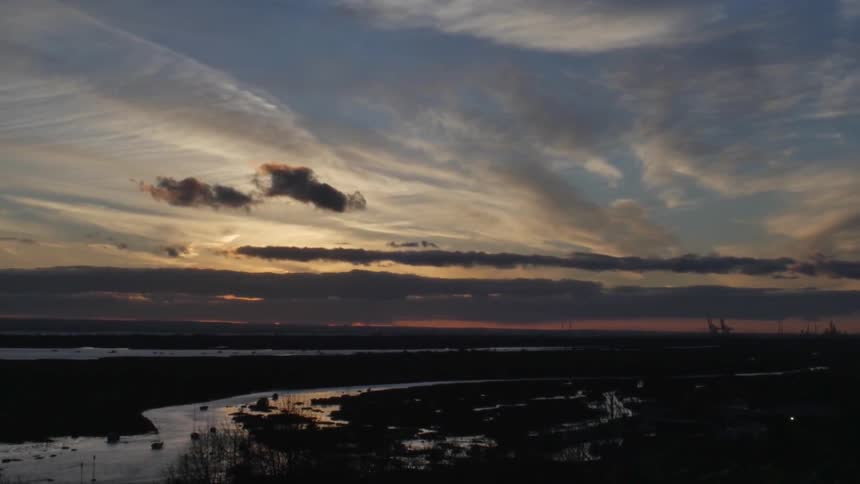 View of the sun setting over a field with water