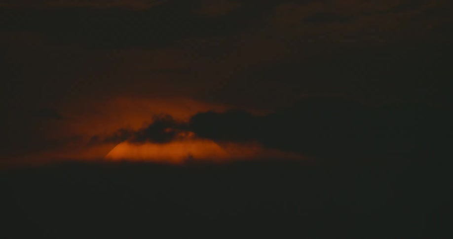 The sky and clouds are orange as the sun sets