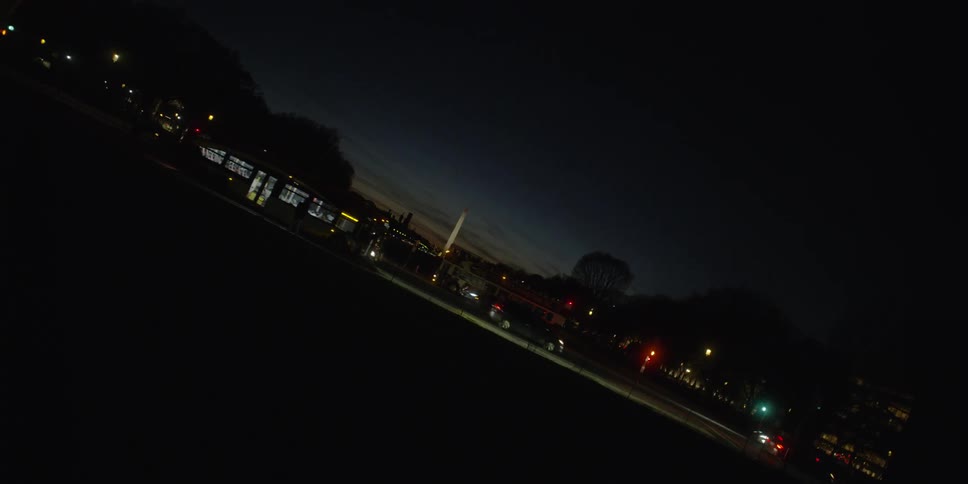 The busy street at night has many cars and buses traveling