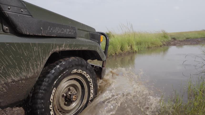 A jeep is driving through some muddy terrain