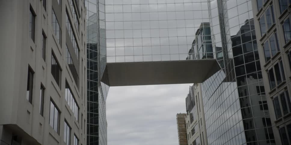 A sky bridge connecting two buildings is viewed from street level