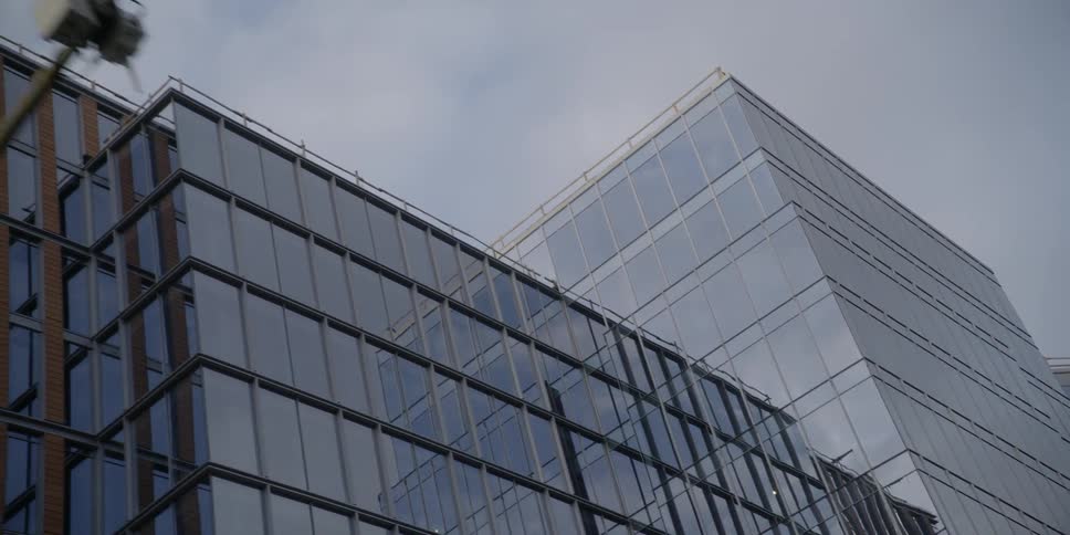 A glass building is filmed from street level