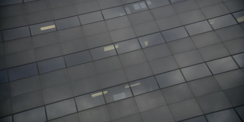A glass building is being filmed from street level