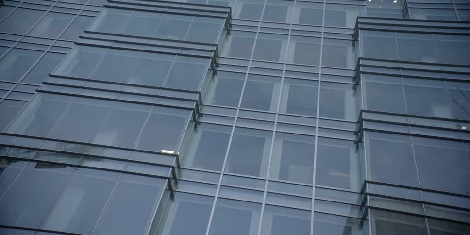 The glass windows of a skyscraper reflect its surrounding at dusk