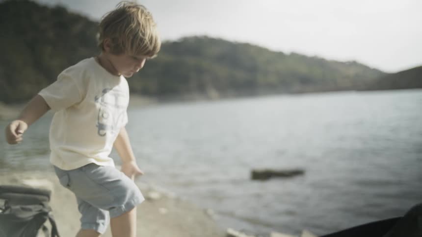 A young boy is getting into a kayak next to a lake